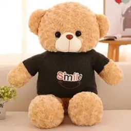 Peach-colored plush teddy bear wearing a black shirt that reads 'Smile' with a small graphic of a smile.